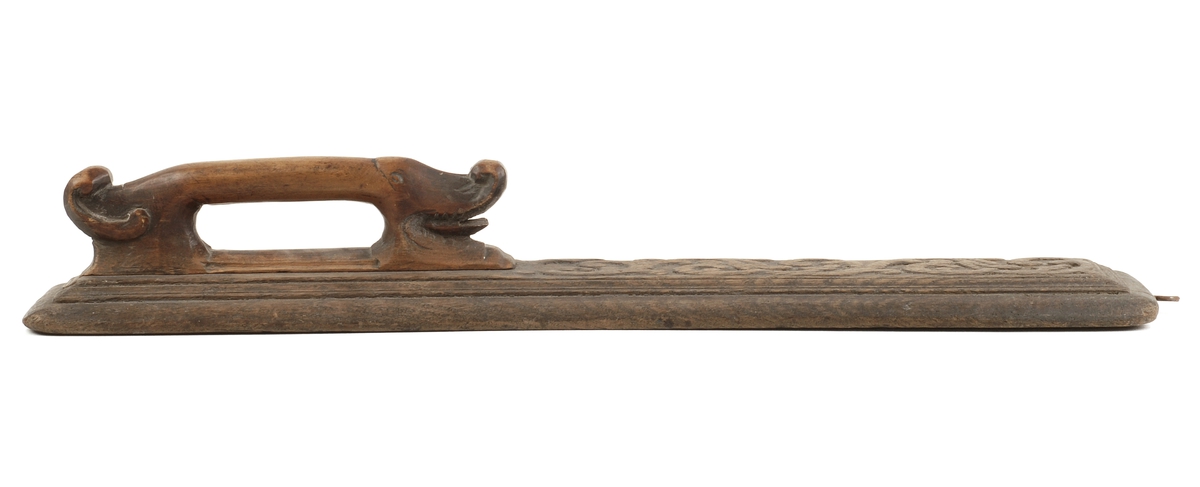 Mangletreets håndtak er utformet som et dyr en drage / bøyle form.
Håndtakssidens overside er dekorert med en utskåret rankedekor i relieff.