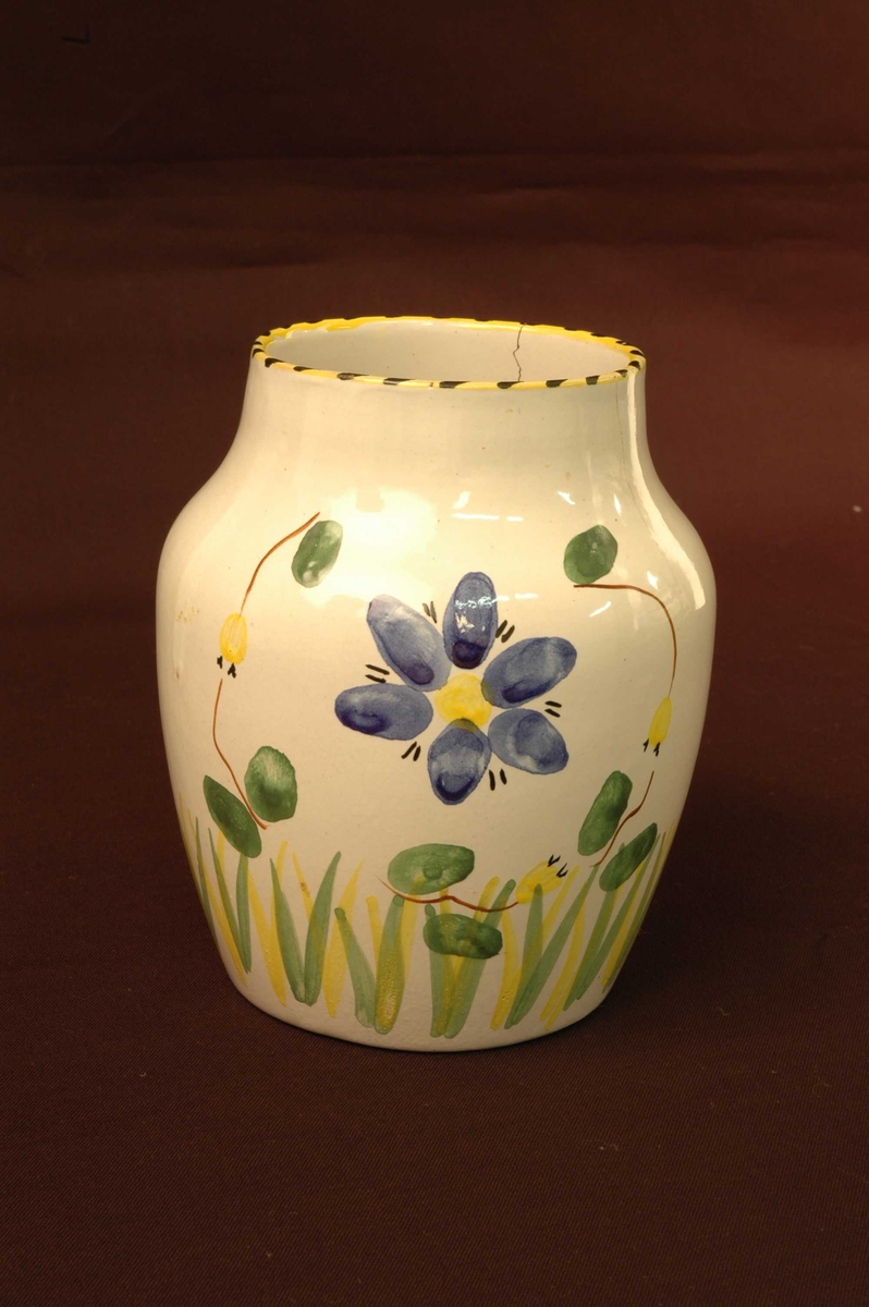 Hvit vase med blomstermotiv i blått, rødt, gult og grønt. 