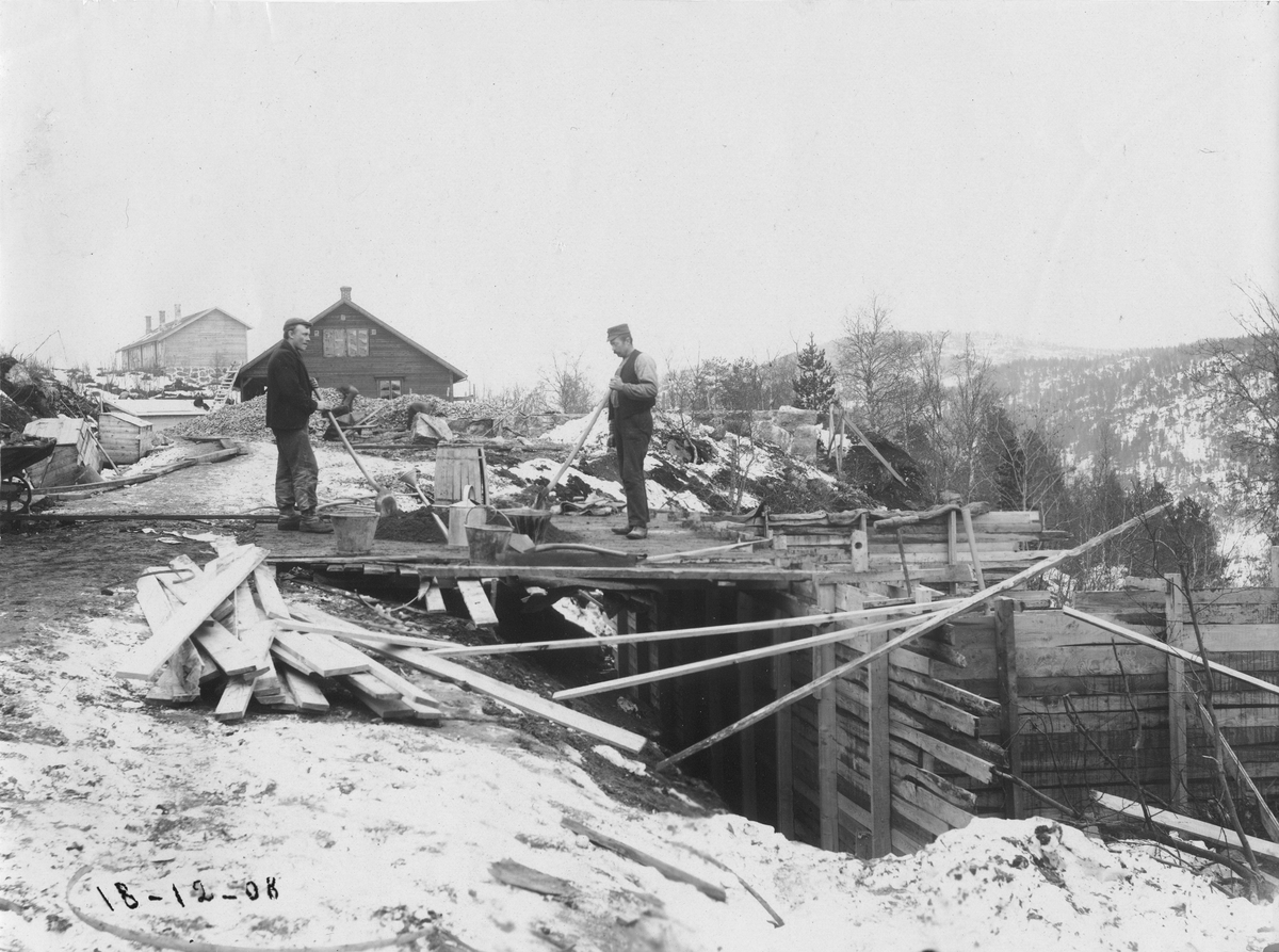 Støping av grunnmurer på formannshus syd for brakke 25. To menn i arbeid.