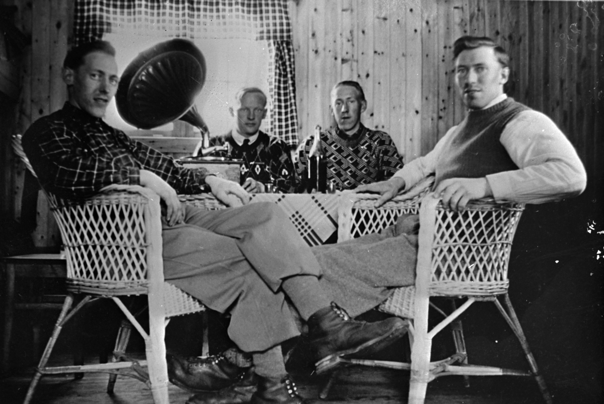 Fire menn i kurvstoler ved bord med sveivegrammofon på. Repro.
