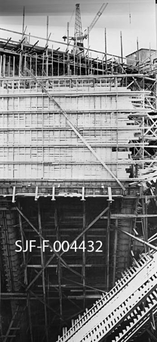Forskalingsarbeid for den nye kraftstasjonsbygningen som ble reist ved Geithusfossen på Modum i Buskerud i 1960-61.  Fotografiet er tatt i november 1960.  Bildet viser hvordan det ble forskalet med tre for de armerte betongkonstruksjonene.  Over det hele troner ei bygningskran.  Motivet er sammensatt av to opptak. 