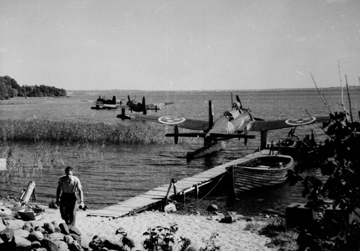 Tre stycken flygplan S 17 på vatten vid brygga på F 2 Hägernäs. En man i förgrunden.