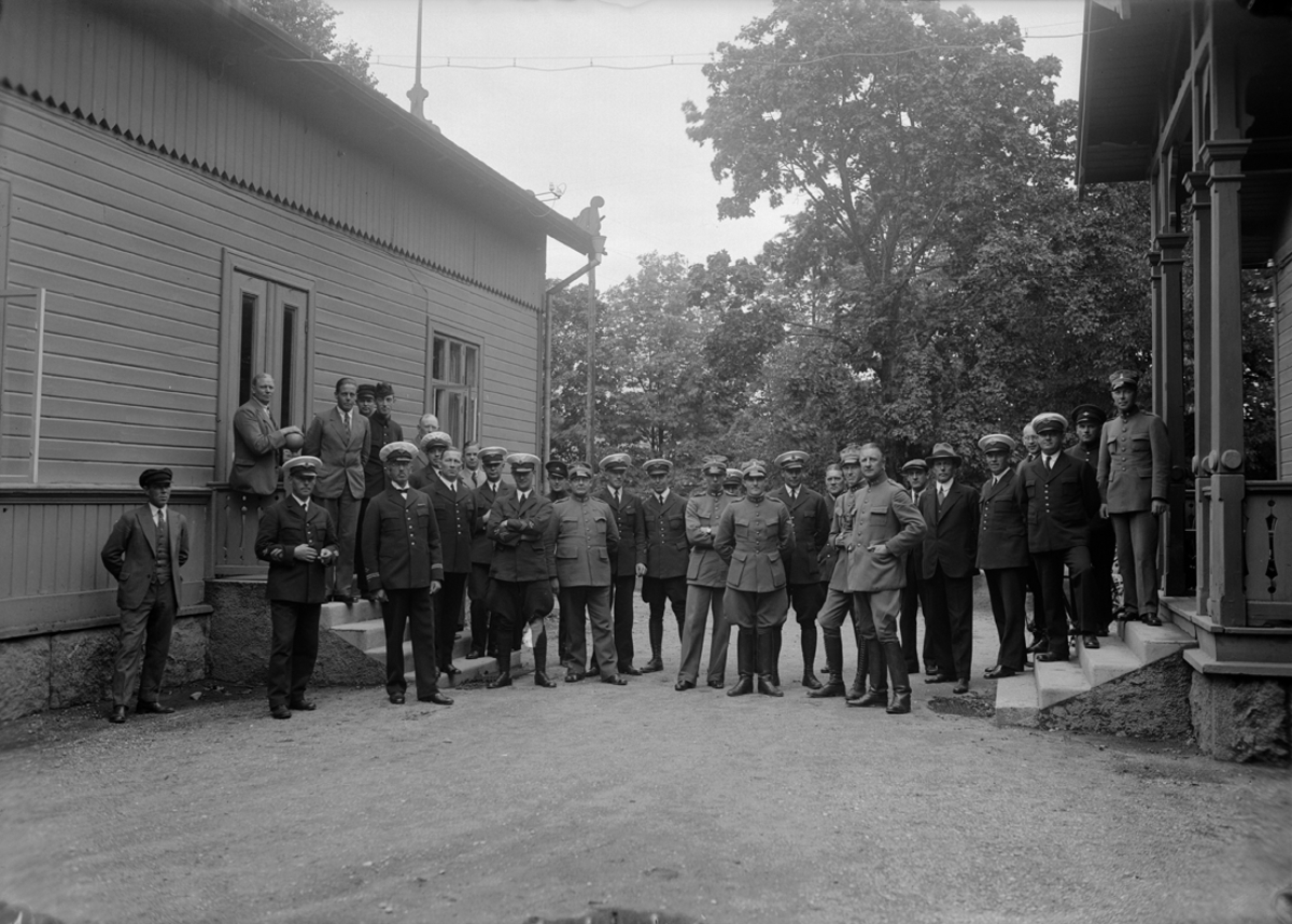 Grupporträtt. Tredje flygkårens personal vid krigsrätten på Malmen 1934-08-31.   Män uppställda mellan två byggnader.