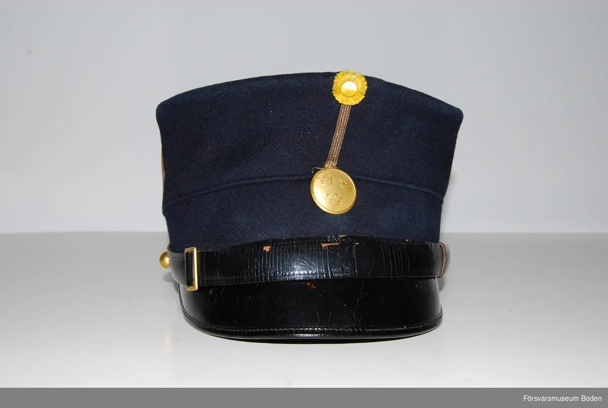 Mörkblått kläde med en smal vertikal galon, betecknande sergeant efter1923. Hakrem av svart läder, fäst med kulknapp modell mindre i guld på sidorna. Framtill gul sidenkokard och mössknapp i guld  för underofficerare.