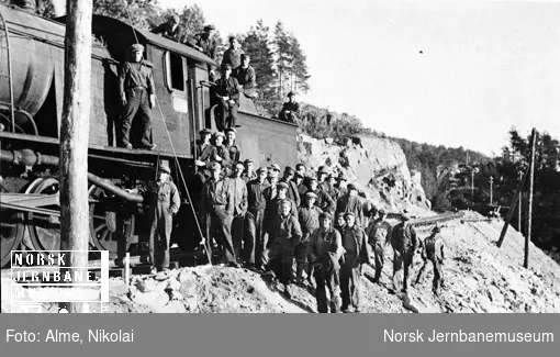 Gruppebilde av en stor gjeng banearbeidere ved siden av damplokomotiv type 33 nr. 324 på sørlandsbaneanlegget