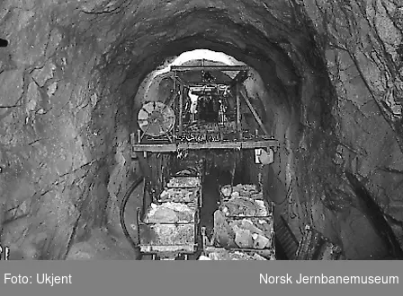 Bukk for framskaffing av trykkluft- og vannledning til boremaskiner m.v. i stuffen i Kvineshei tunnel, vestre innslag. I forgrunnen lastede vagger