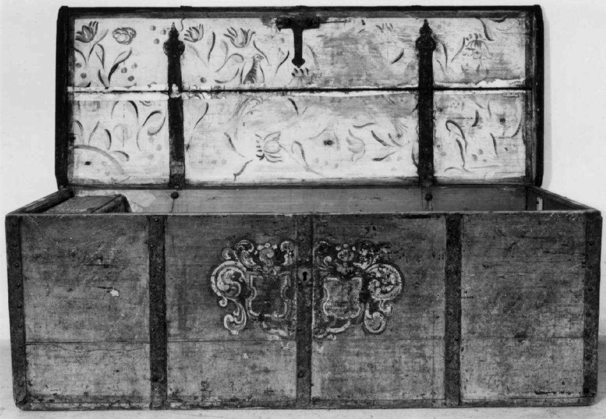 Kiste med flatt lokk og smijernsbeslag og bånd. På fronten malt to våpenskjold, på kortsidene marmorert. Innsiden av lokket er også malt.