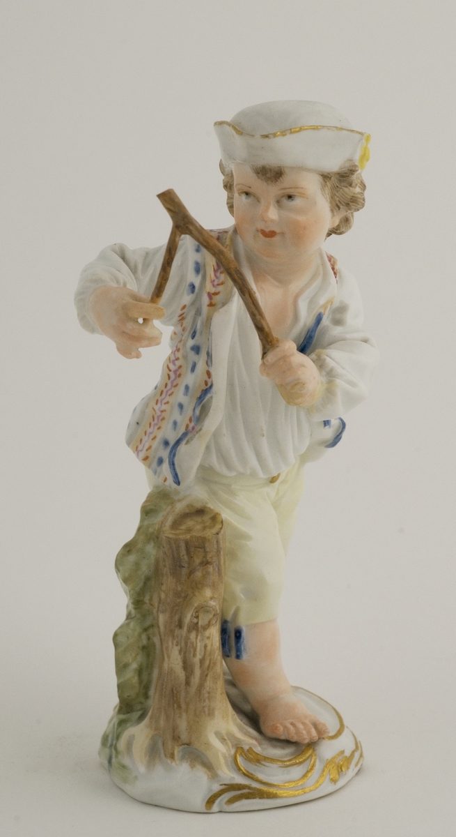 Figur; porselen, gutt med åpen vest, grå snutehatt. Merket 11 med rødt under fotplaten.