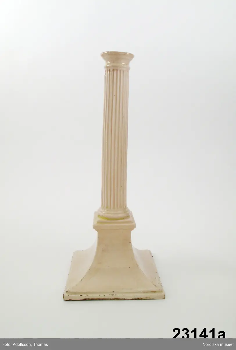 Ljusstake av flintgods, på hög, insvängd kvadratisk fot, räfflat kolonnskaft. Omärkt, troligen tillverkad i England omkring 1800.
/Annika Tegnér 2008