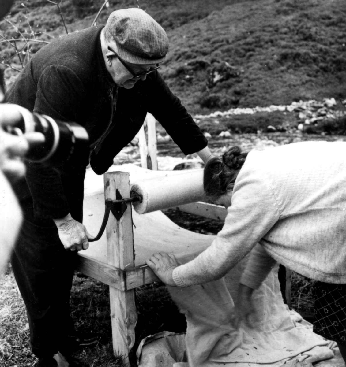 Stamping av vadmel. Serina og Ingemund Kvæstad vinder opp ferdigskylt vadmelstøy på et stativ. Kvæstad, Suldal, Rogaland 1970.