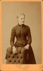 Visittkort. Portrett av kvinne stående bak stol.