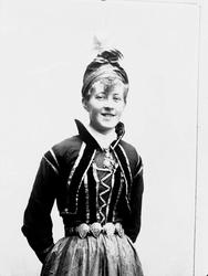 Studioportrett av ung mann i drakt og lue.