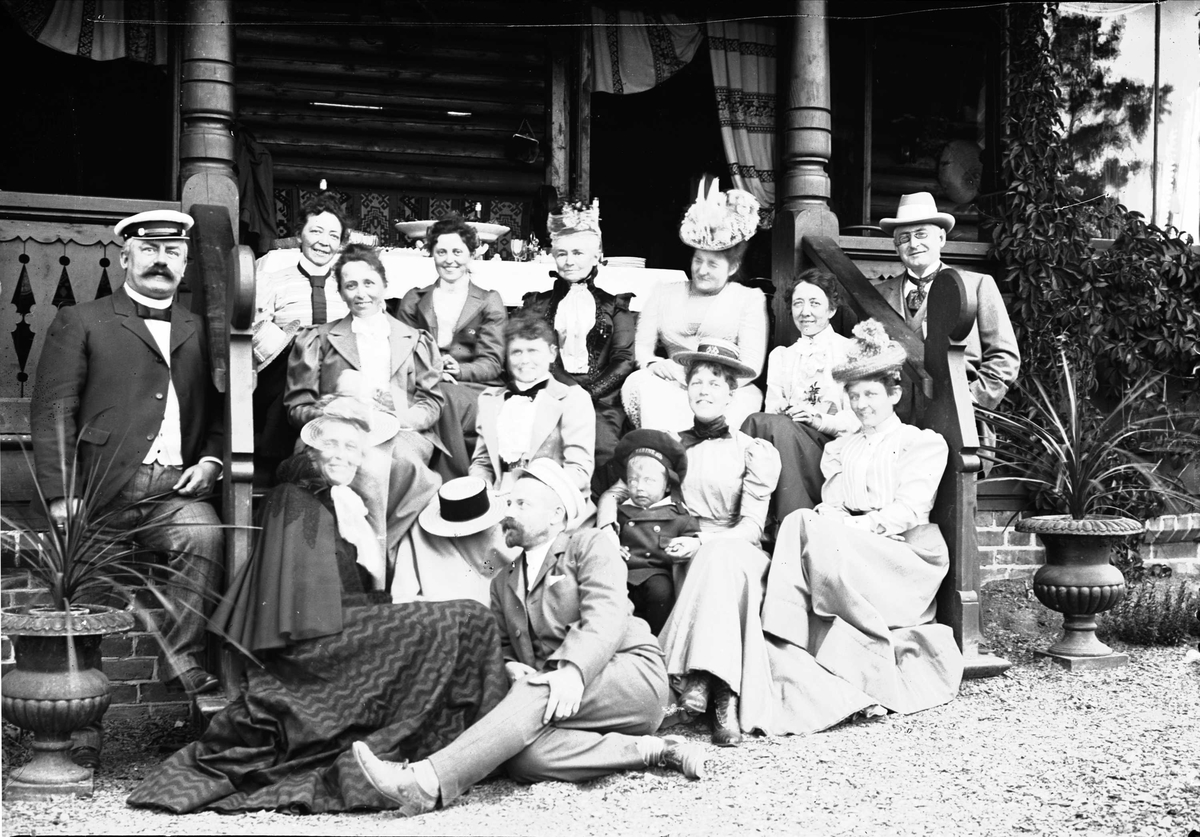 Familieportrett, stor gruppe mennesker foran inngangsparti og veranda. Muligens Villa Grande, Drøbak, Frogn, Akershus. Antagelig familiene Hansen og Lund, ca 1900-1905.