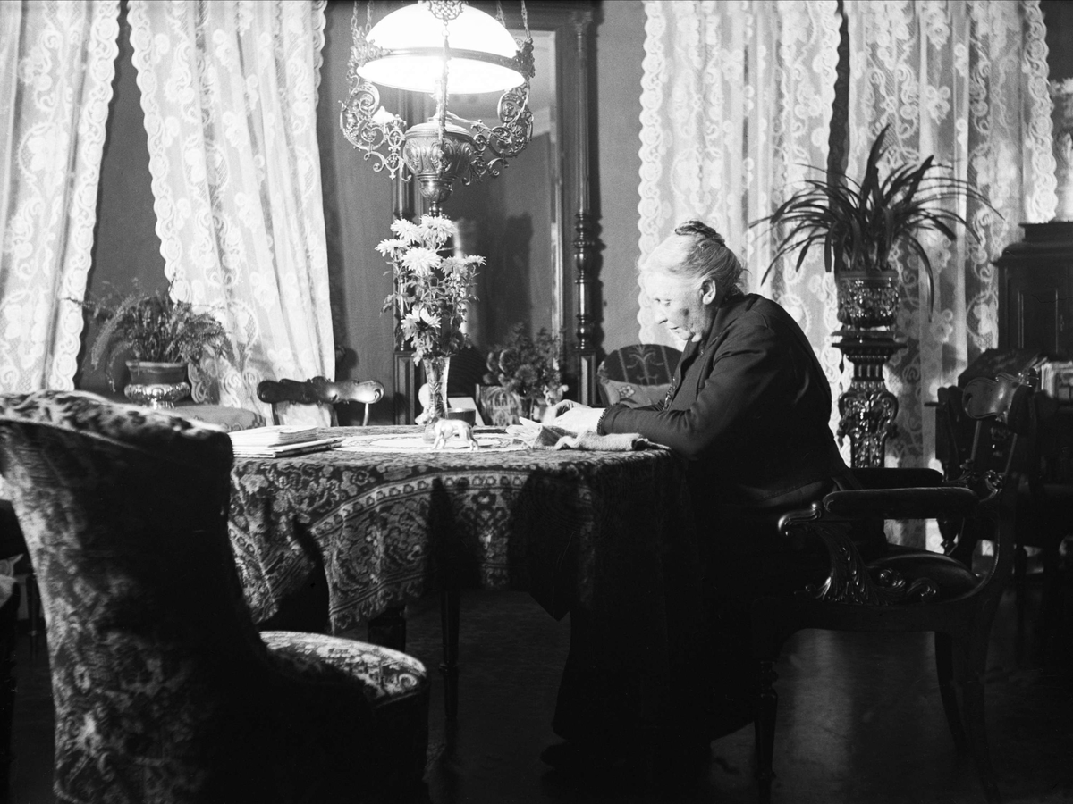 Andrea Leegaard sitter i hjørnerommet ved et bord, Fredrikstad. Fotografert januar 1926.
