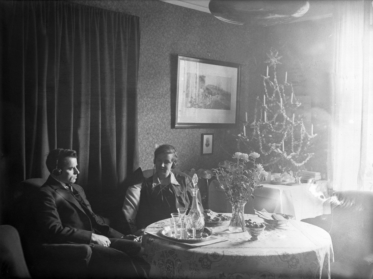 Fritjof og Dordi Arentz hører på radio med høretelefoner på 1. juledag i Kirkeveien 78C 3. etg., Majorstuen. Fotografert 25. desember 1928.