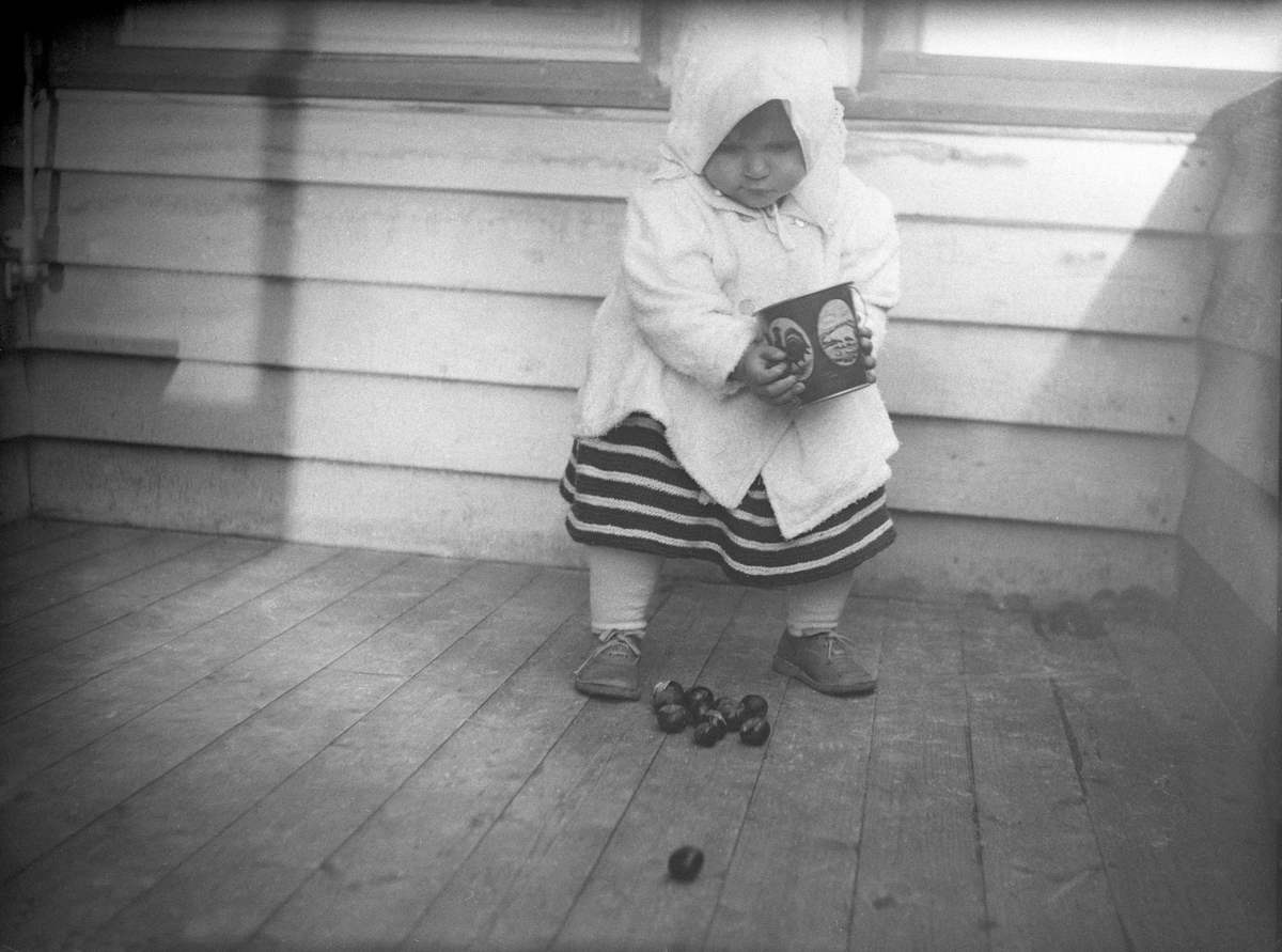 Guri Arentz står på verandaen med et spann med kastanjenøtter. Fotografert oktober 1930.