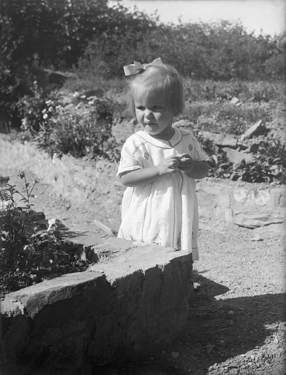 Siri Arentz står ved siden av et blomsterbed. Fotografert 1932.