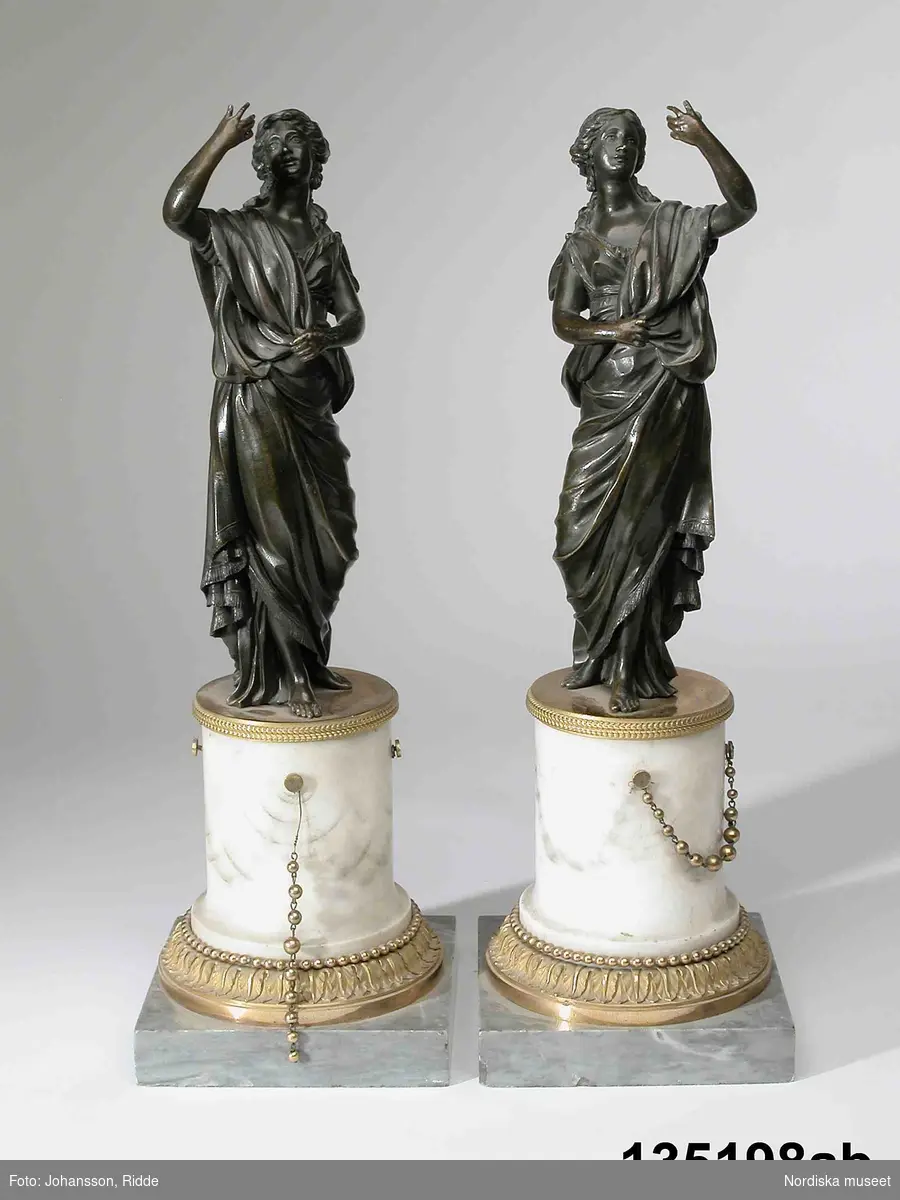 Hvuvudliggaren:
"Armljusstakar, 1 par, av brons och marmor, kvinnofigurer, uppbärande liljestänglar; för 3 ljus."

Även 6 st (2 x 3 st) ljuspipor till ljusarmarna.
Leif Wallin 2005-01-14