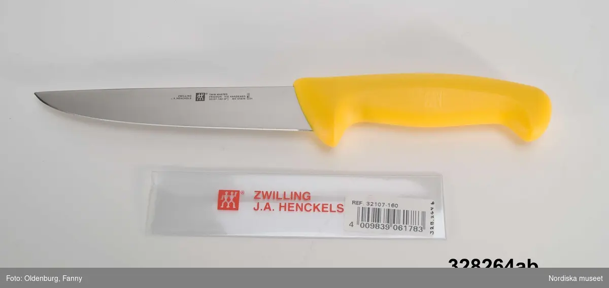 A-B:
a) Stickkniv avsedd för slakt, blad av rostfritt specialstål med ett kraftigt handtag i gul polypropylenplast. 
b) Eggskydd av genomsynlig plast skyddar knivbladet och den som hanterar den skarpa kniven, tryckt text i rött "ZWILLING J.A. HENCKELS" samt firmasymbol, påklistrad streckkodsetikett.

Kniven tillverkad i Solingen av en av Tysklands mest namnkunniga knivsmedjor. Tål maskindisk. Kniven används för att sticka det av slaktpistolen bedövade slaktdjuret. Med kniven gör slaktaren ett par snitt i djurets kroppspulsåder i halsen. I samband med att blodet lämnar djurkroppen dör djuret. Kniven uppfyller moderna krav på god hygien och är lätt att hålla ren från blod och hårrester.
Se även inv.nr 328262 slaktpistol och 328263 ammunitionsask.
/Johan Åkerlund 2005-10-17