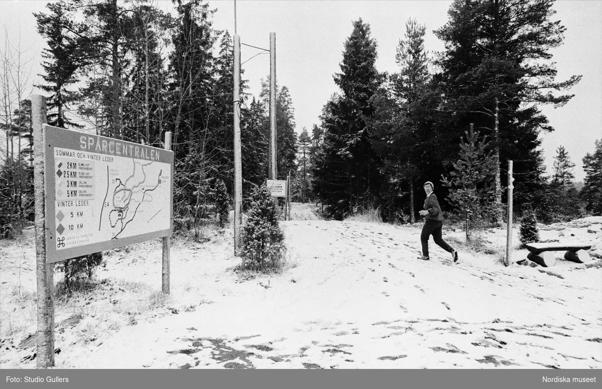 Joggare i motionsspåret. En skylt "Spårcentralen" visar de olika slingornas sträckning i skogen. Hemlingby, Gävle. 