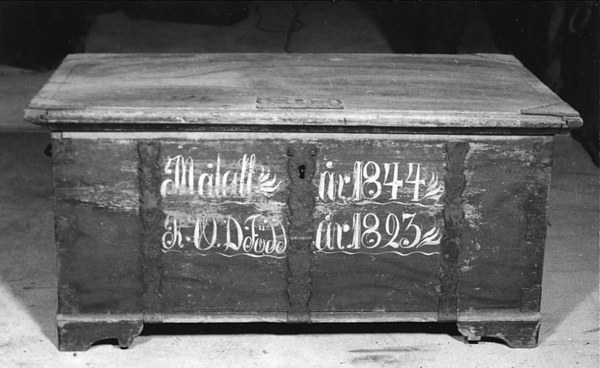 Kista av trä. Brunmarmorerad med blåmålade kanter på locket och blå järnbeslag. Med vitt står: Målatt år 1844 K. D. D. Född år 1823. På locket ett beslag med text: 1839 C P D. Läddika med lock.