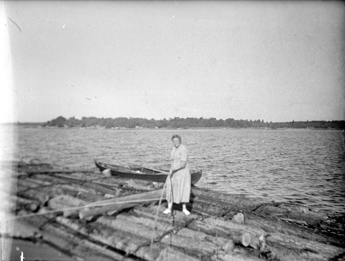 Kvinna på buntade timmerstockar, Tierpstrakten, Uppland omkring 1915 - 1920