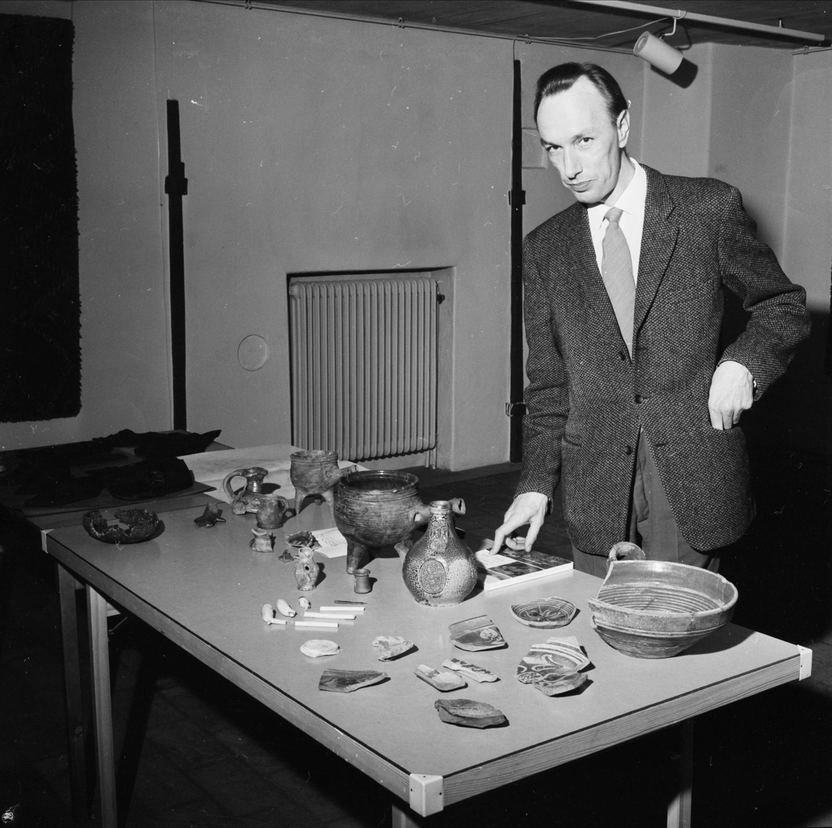 Lars Gezelius visar arkeologiska fynd som tillvaratagits vid schaktningar i kvarteret Duvan vid Smedsgränd, Uppsala 1962