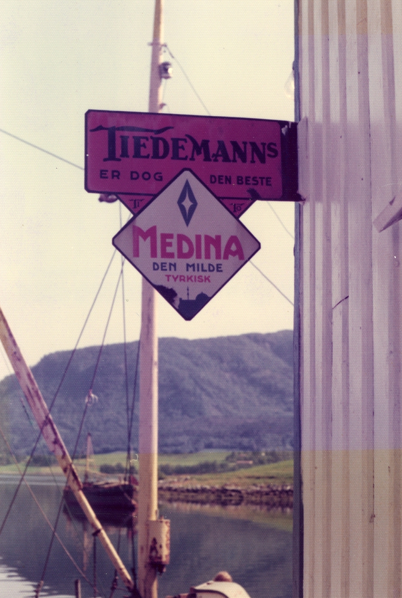 Skilt med reklame for Tiedemanns Medina sigaretter på fasade.