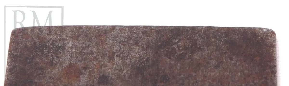 Rektangulær plate av jern med håndtak i ene enden. Håndtaket har en liten bøy. Merker viser 1-12 tommer