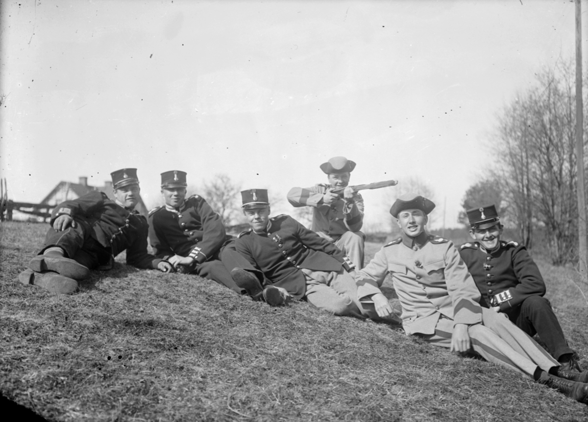 Grupporträtt. Sex armésoldater från I 4 och / eller I 5 regemente sitter i en backe. En av männen lägger an en träpinne som ett låtsasgevär.