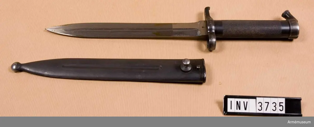 Knivbajonett m/1896 t gevär m/1896, m/1938/automatgevär m/1942.Består av: 1 bajonett, 1 balja av stål.Helt tillv. av stål med rörformigt lättrat grepp med konisk låsknapp och pipring. Rak, eneggad klinga med smal blodskåra på båda sidor. Klingb vid fästet: 25 mm. Pipringens id: 15,5 mm. Balja, l: 232 mm, vikt: 120 gr; tillv.nr 118.