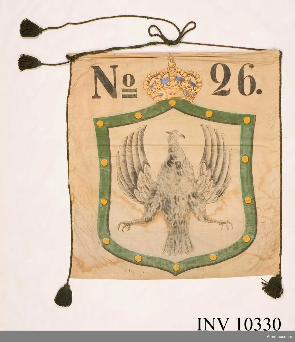 Grupp B I.

Bottentyg av vit lärft. Långsidorna är kantade med grön bomullssnodd avslutad i tofsar. Två tofsar på den ena sidan, en på den andra. Målad sköld krönt med kunglig krona och märkt No   26. Värmlands vapen i skölden. Standaret är fastspikat vid en träribba.1948-12-17 ink. 481, utdrag ur brev från kapten O Oxehufvud: "Den förra är målad af d.v. löjtnanten Herman Byström och användes vid officerskårens bal 1882 för att bjuda cottillonsdekorationer åt damerna af en liten hornblåsare" ...