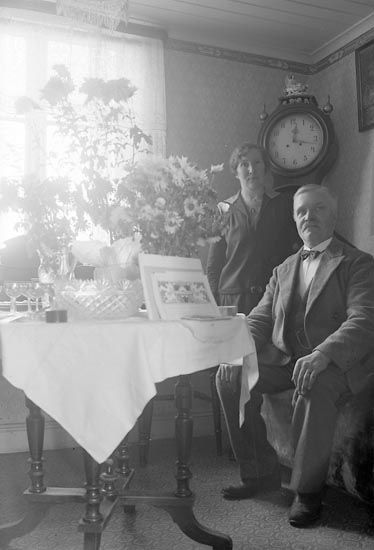 Man och kvinna poserar framför fotografen i en vrå av finrummet.
