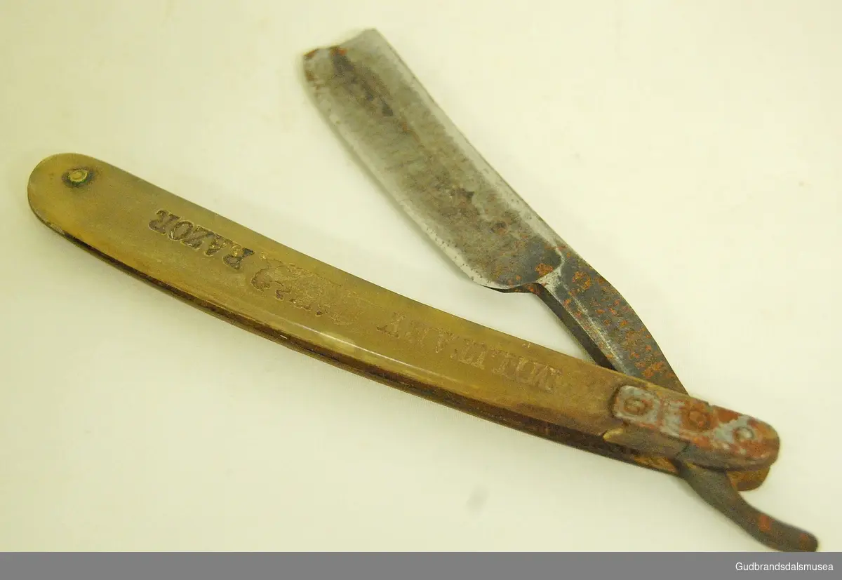 Sammenleggbar barberkniv i stål, med håndtak av bein, håndtak lett buet. Knivhals naglet til håndtak. 