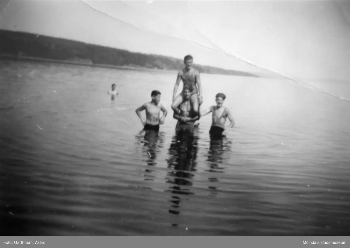 Fyra män som badar i sjön Lygnern, 1930- 40-tal. Från vänster: okänd i bakgrunden, Gösta Gunnarsson, okänd med Helmer Garthman på axlarna samt okänd till höger.
