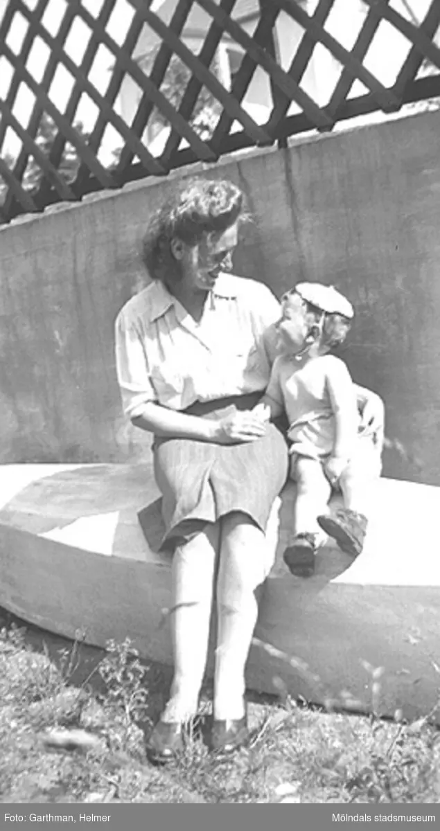Astrid Garthman och sonen Leif-Åke sitter på en bänk och tittar kärleksfullt på varandra. Mölndal, 1944. Broderrn till Leif-Åke, Alf Garthman, arbetade många år på Mölndals stadsmuseum.