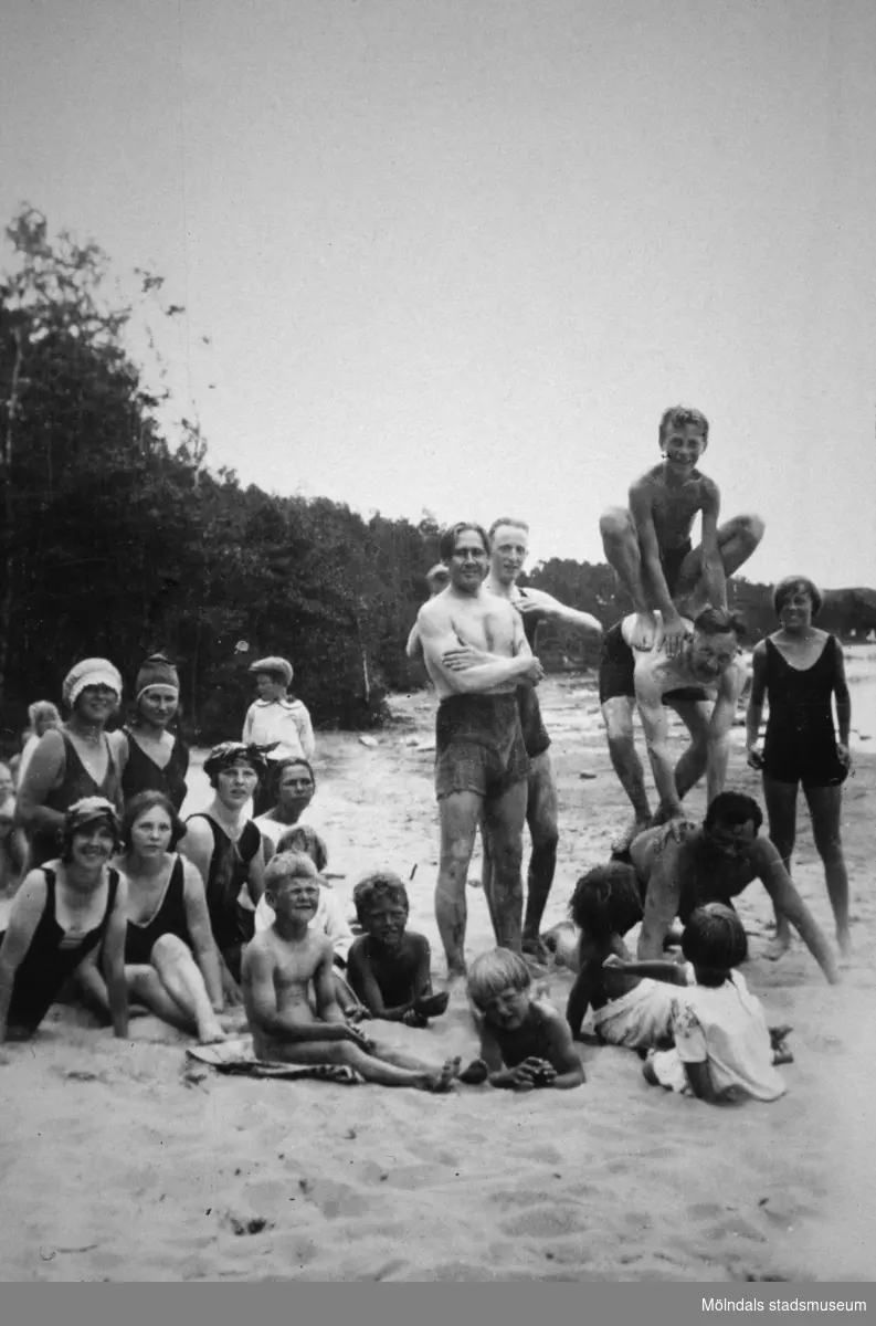 Män, kvinnor och barn på en strand (bekanta till familjen Alberts) vid Tulebosjön, 1930-tal. Några utav dem bygger en mänsklig pyramid.
