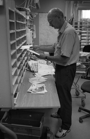 Lantbrevbärare Reinhold Andersson sorterar post inne i
sorteringsdelen på en postanstalt. Tillhör en dokumentation av en
lantbrevbärare i trakten av Valdermarsvik av fotograf Ove Kaneberg.