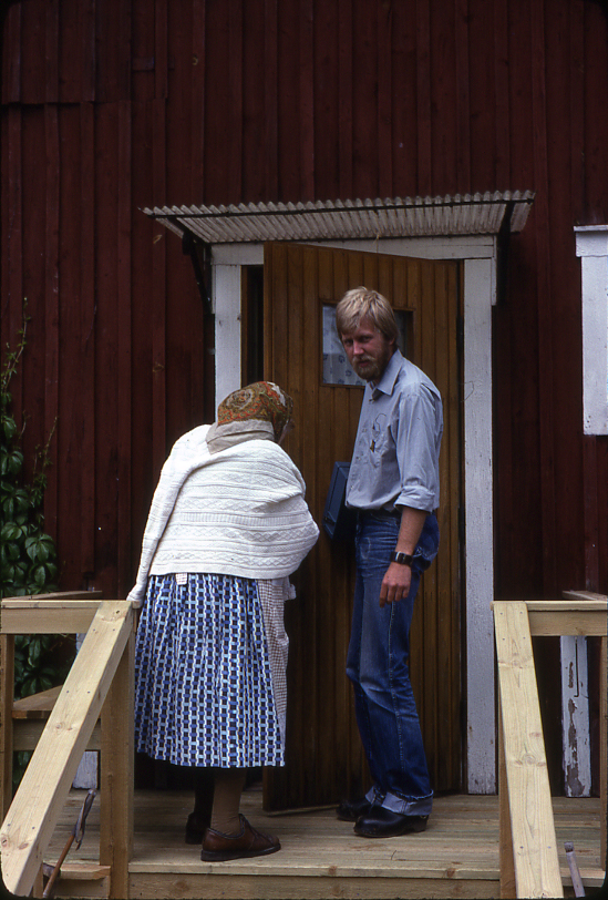 Lantbrevbärare Mikael Mattsson har kommit till Rockstaberg. Han står med Ester Gustavsson på trappan till hennes hus. De är på väg in genom dörren. Kassaskrinet har han under armen.