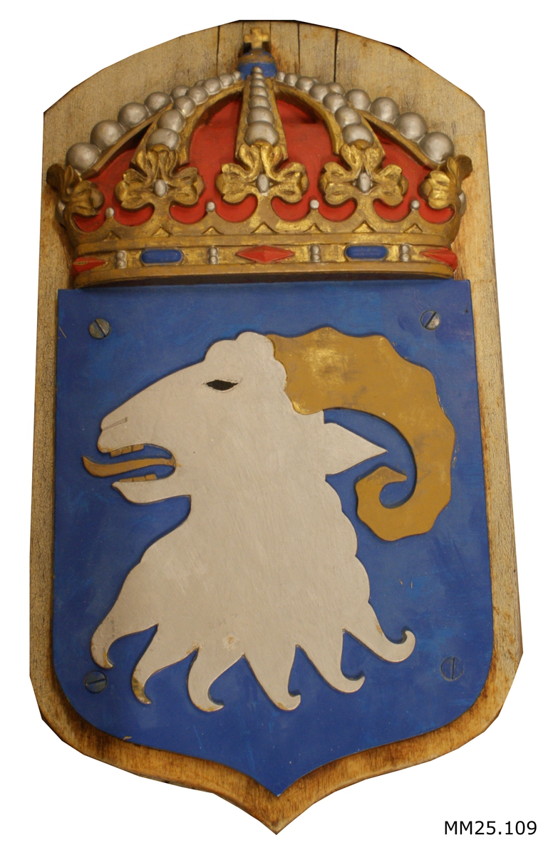 Vapensköld i metall på fernissad träplatta. Motivet föreställer en bock med utsträöckt tunga på blå botten. Krönt med krona.