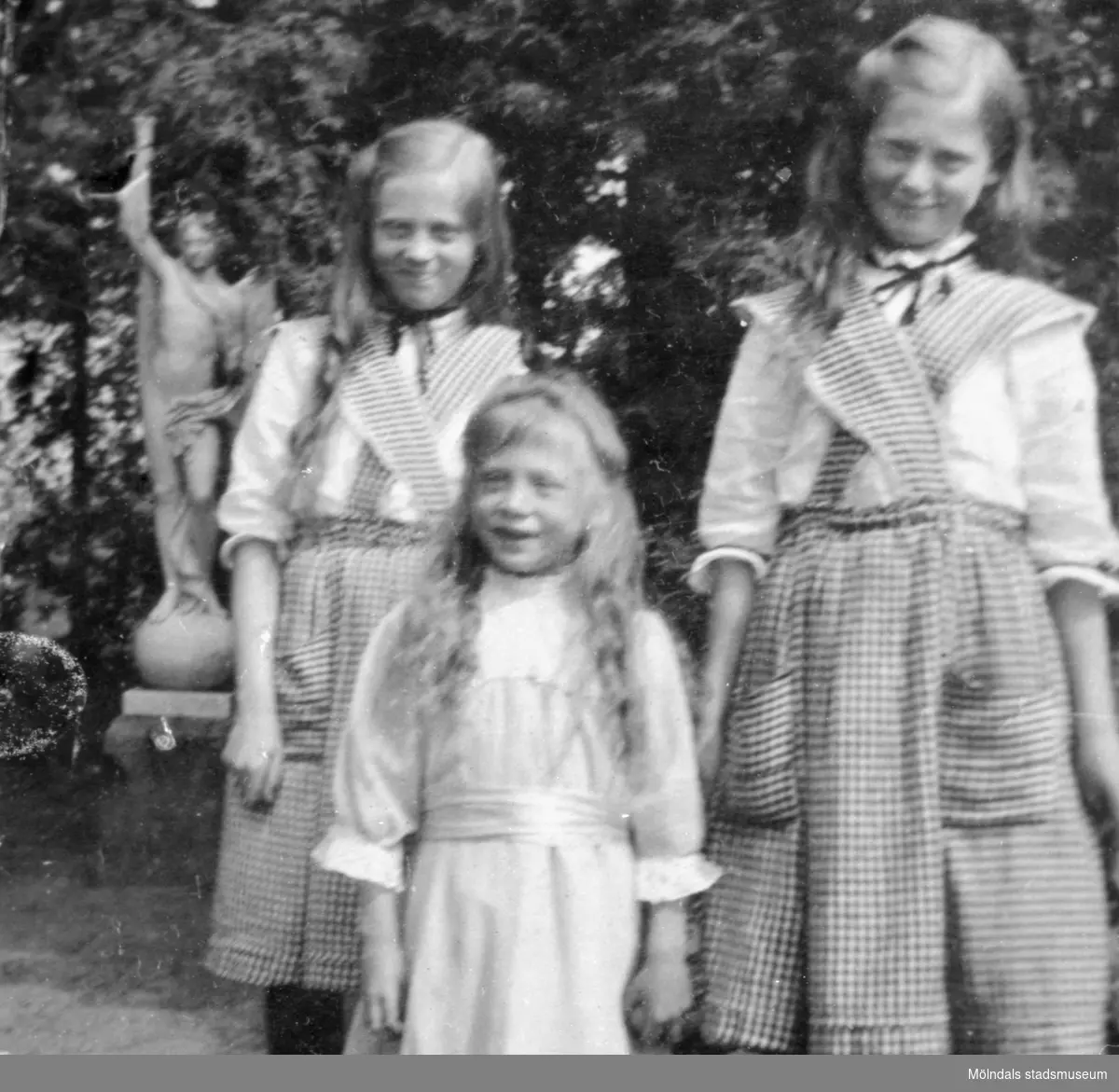 Systrarna Lindblom poserandes utomhus. Astrid, Hildur och lilla Calla framför. Man ser en staty i bakgrunden. 1930-40-tal. Döttrar till Gunnebo slottsanställda Karl August (1870-1949) och Hilma Sofia Viktoria (1876-1921) Lindblom.
