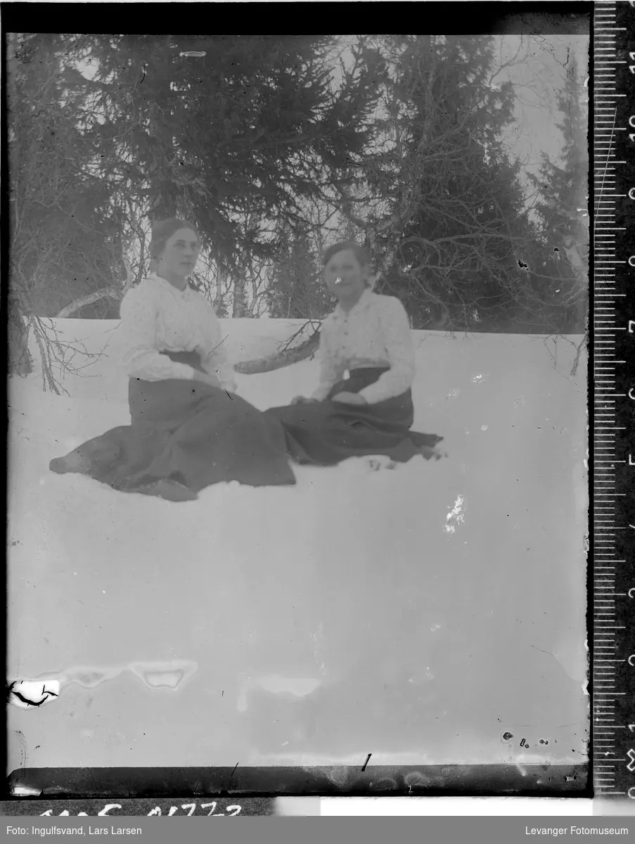Portrett av to kvinner som sitter i snøen.