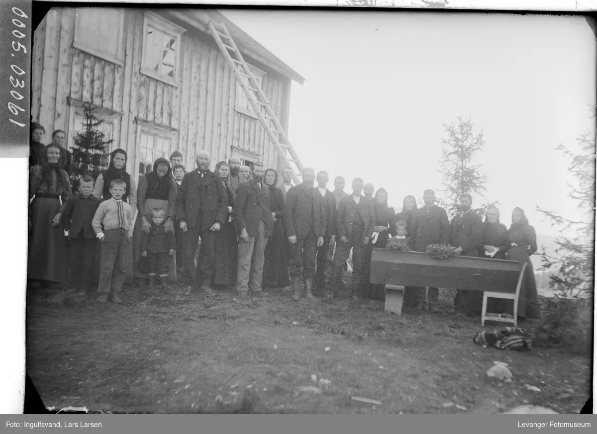 Forsamling av mennesker med kista før begravelsen.