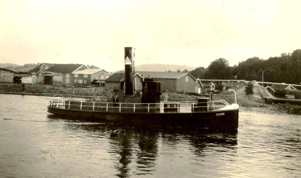 Slepebåten "Stærk" med trebygninger i bakgrunnen