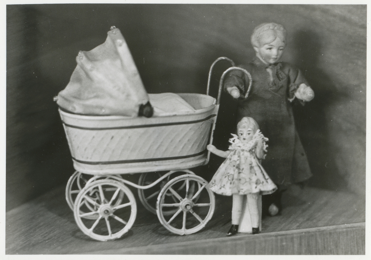Gjenstandsfotografi av to dukker og en dukkevogn fra en tidligere utstilling på Sunnmøre Museum, "Barn på Sunnmøre". Lekene skal være fra 1910-årene.