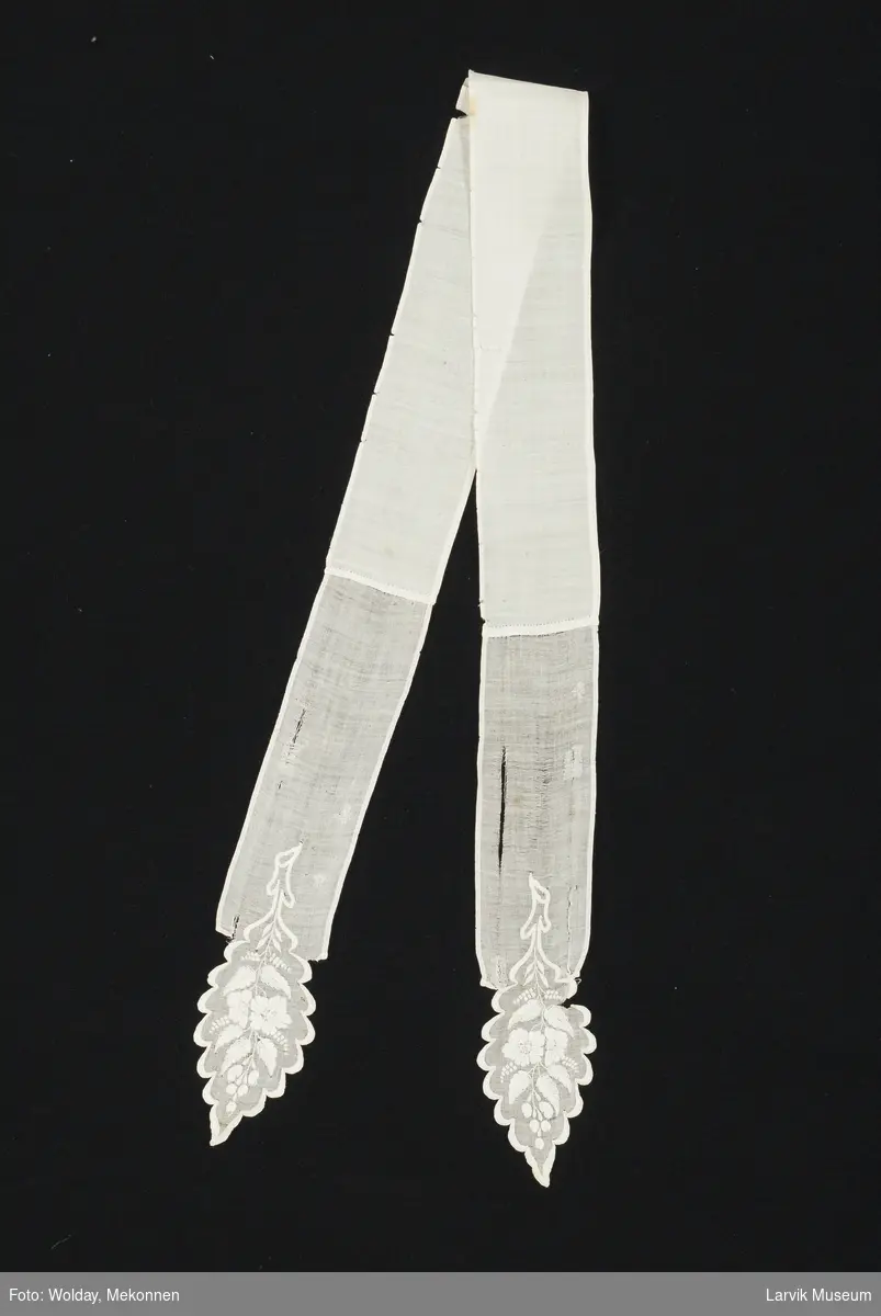 Form: hvit batist,finere kvalitet i endene som har hvitsøm, kortenden er bladformet med buer i knapphullsting 
