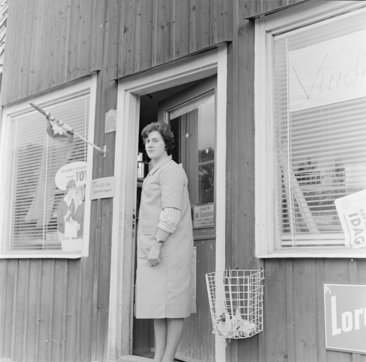Kvinna utanför "Hagby diversehandel", Uppland 1962