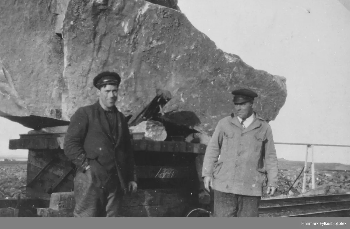 Her poserer Levio Offershøy frå Lofoten, som var skytebas, og Johan Schanche, arbeidsformann i bruddet eller 'fjellet', foran jernbanevognen med en stein på 20 tonn. Dette er verdens nordligste jernbane. Steinen ble brukt i moloen i Berlevåg