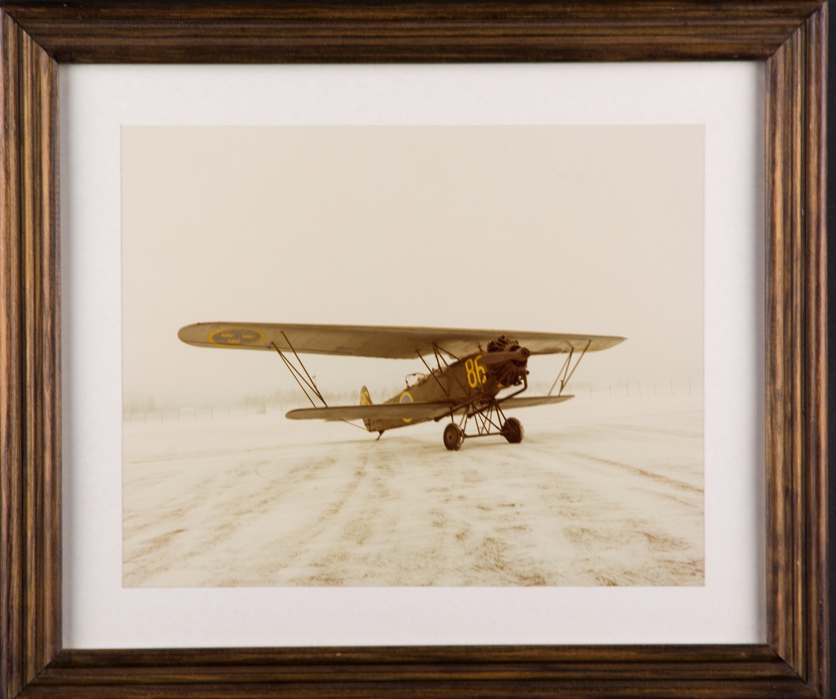 Flygplan S 6B nummer 386 står på ett fält på Malmen, vintertid. Inramat foto.
