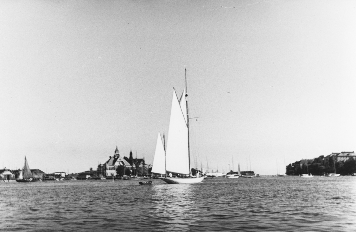 År 1936 företog flera båtar ur KSSS en eskadersegling ("Sjötåget till Helsingfors") för att deltaga i Nyländska Jaktklubbens 75-årsfirande med åtföljande regatta. Bilden är tagen fredagen 9 juli i samband med eskaderns ankomst till Helsingfors. I bakgrunden NJK:s klubbhus på Blekholmen.